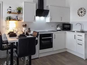uma cozinha com armários brancos e uma mesa com um lavatório em Castlegate em Lanark