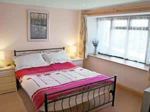 a bedroom with a bed with a red and white comforter at Skellgill Barn in Bainbridge