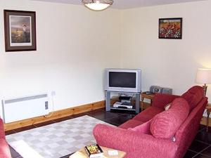 a living room with a red couch and a tv at The Old Stables in West Ashby