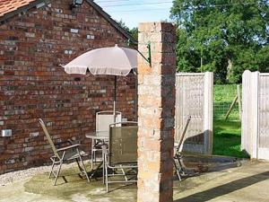a brick building with a table and an umbrella at The Old Stables in West Ashby