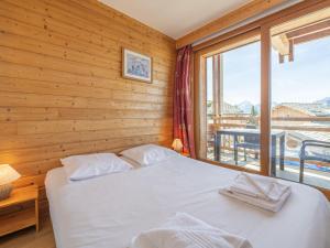 une chambre avec un lit et une grande fenêtre dans l'établissement Appartement au centre de la station avec balcon dans chalet, animaux acceptés - FR-1-645-45, à Huez
