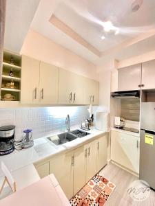 - une cuisine avec des placards blancs et un évier dans l'établissement Homestay by ViJiTa 2bedroom condo, à Manille