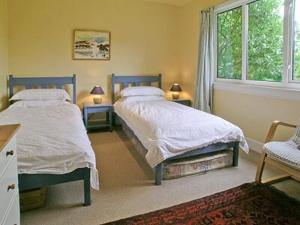 a bedroom with two beds and a window at Ardura Cottage in Lochdon