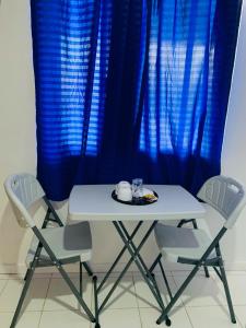 een witte tafel en stoelen met blauwe gordijnen bij The Victorian by Stevrena Accommodations in Ocoy