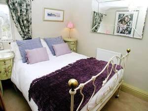 ボウネス・オン・ウィンダミアにあるRustic Cottageのベッドルーム1室(紫色の毛布と枕が備わるベッド1台付)