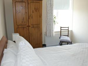席維戴爾的住宿－Shore Cottage，卧室配有白色的床和木制橱柜。