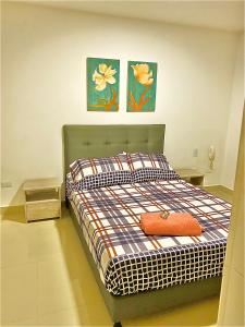 Bett in einem Zimmer mit zwei Bildern an der Wand in der Unterkunft Apartamento completo in Ibagué
