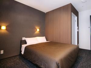 a bedroom with a bed and two lights on the wall at Hotel Trend Takatsuki in Takatsuki