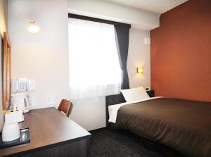 a hotel room with a bed and a desk and a window at Hotel Trend Takatsuki in Takatsuki