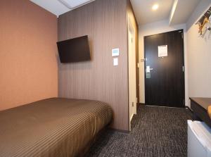 a room with a bed and a door with a television at Hotel Trend Takatsuki in Takatsuki