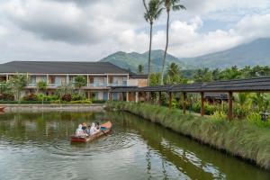 people in a canoe on a river in front of a building at Villa Rancabango Hotel & Resort Garut in Tarogong