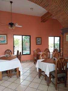 un comedor con mesas, sillas y ventanas en Hotel Parador del Rey, en Temixco