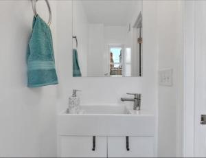 a white bathroom with a sink and a mirror at Quaint 3/2.5 home in Fort Dupont in Washington, D.C.