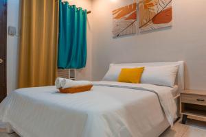a bedroom with a white bed with yellow and blue curtains at GT Seaside Inn in Oslob