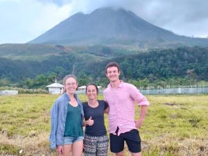a man and two women standing in a field with a mountain in the background at Ustin Nagoya Bukit Lawang Orangutan Trekking & transport You can only stay at the hotel if you book your trekking with us in Bukit Lawang