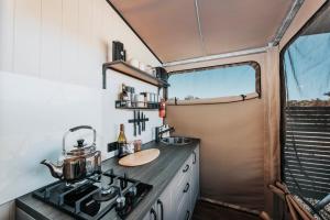 una cocina con fogones y fregadero en una cabaña en Wildnest Farmstay en Capertee