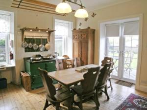 a dining room with a table and chairs and a kitchen at The Dell in Fort Augustus