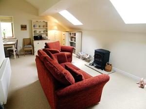 a living room with two red chairs and a stove at Owl Cotes Cottage in Cowling