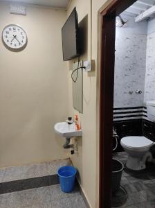 a bathroom with a toilet and a clock on the wall at DANDELI CROCODILE EDGE HOME STAY in Dandeli