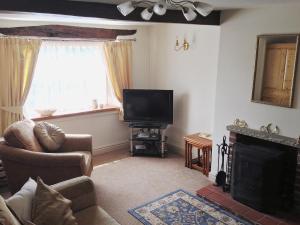 a living room with a fireplace and a television at Jug And Glass Cottage in Upper Langwith