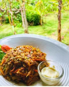 a white plate of food with a bowl of sauce at Bundala Flamingo Cotteges in Hambantota