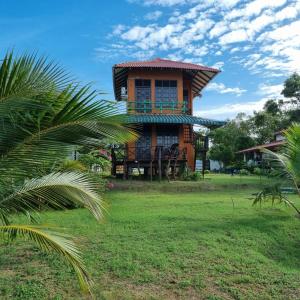 a building with a balcony on top of a grass field at Bundala Flamingo Cotteges in Hambantota