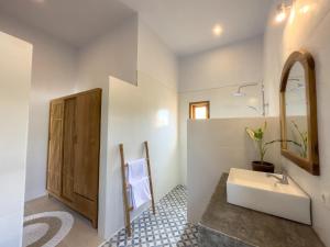 een witte badkamer met een wastafel en een spiegel bij Villa Alamanda in Kuta Lombok