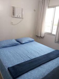 a bedroom with a bed with blue sheets and a window at Sinta-se em casa! Lindo Ap para você e sua família in Manaus