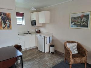 eine Küche mit weißen Schränken sowie einem Tisch und Stühlen in der Unterkunft Commodore Motor Lodge in Ashburton