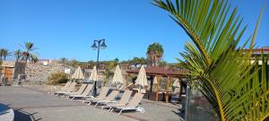 - une rangée de chaises longues et de parasols dans un complexe dans l'établissement Duplex Anfi Topaz, à Mogán
