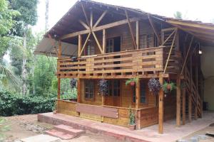 a wooden house with a bench in front of it at Coorg Northbreeze Wooden Stay in Madikeri