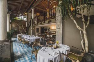 a dining room with white tables and chairs at Luwak Ubud Villa in Ubud