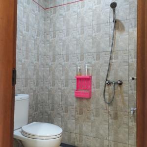 a bathroom with a shower with a toilet and a pink shelf at Santhi Graha by NauliTabitha in Legian