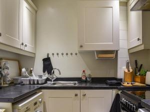 a kitchen with white cabinets and a sink at Kingsway Apartment in Langstone