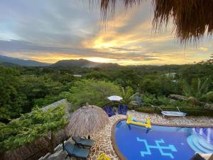 un complejo con piscina, sillas y puesta de sol en Quetzal Dorado Eco-Lodge, en El Zaino