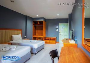 una camera d'albergo con 2 letti, un tavolo e una scrivania di Horizon Hotel a Suratthani