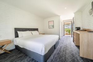 una camera da letto con un grande letto bianco e una finestra di Lakeview Hotel Motel a Shellharbour