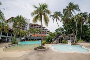 a resort with a swimming pool and palm trees at Sabah Hotel in Sandakan