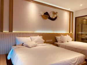 a hotel room with two beds with white sheets at Lighthouse Apec Mũi Né in Phan Thiet