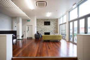 un bureau avec une personne assise sur un canapé dans une pièce avec fenêtres dans l'établissement The Brownston Hostel, à Wanaka