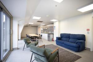 uma sala de estar com um sofá azul e cadeiras em The Brownston Hostel em Wanaka