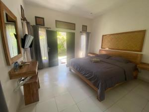 a bedroom with a bed and a desk and windows at Ashana Hotel in Uluwatu