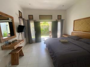 a bedroom with a bed and a mirror and a television at Ashana Hotel in Uluwatu