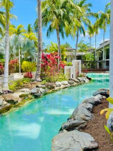 a swimming pool with palm trees in a resort at Lagoon Swimout Absolute Pool Front - Slice of Paradise - Sea Temple Pt Douglas in Port Douglas