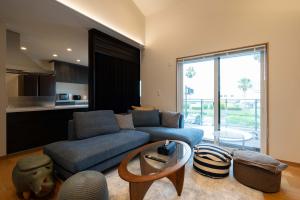 Una sala de estar con un sofá azul y una mesa. en SAKURA house Marine, en Ito