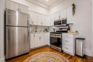 uma cozinha com armários brancos e um frigorífico de aço inoxidável em Charming 1BD/1BA Studio; walk to stadiums & UMD em Baltimore