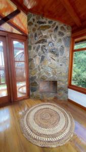 a stone fireplace in a room with a rug at Tiny Celina House in Baños