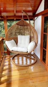 a wicker swing chair on a porch at Tiny Celina House in Baños