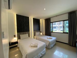 a hotel room with two beds and a window at President Hotel Udonthani in Udon Thani