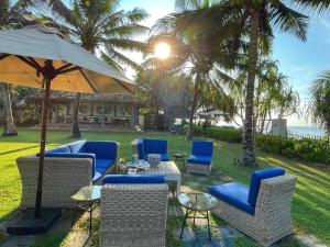 a patio with chairs and tables and an umbrella at Elysium in Unawatuna